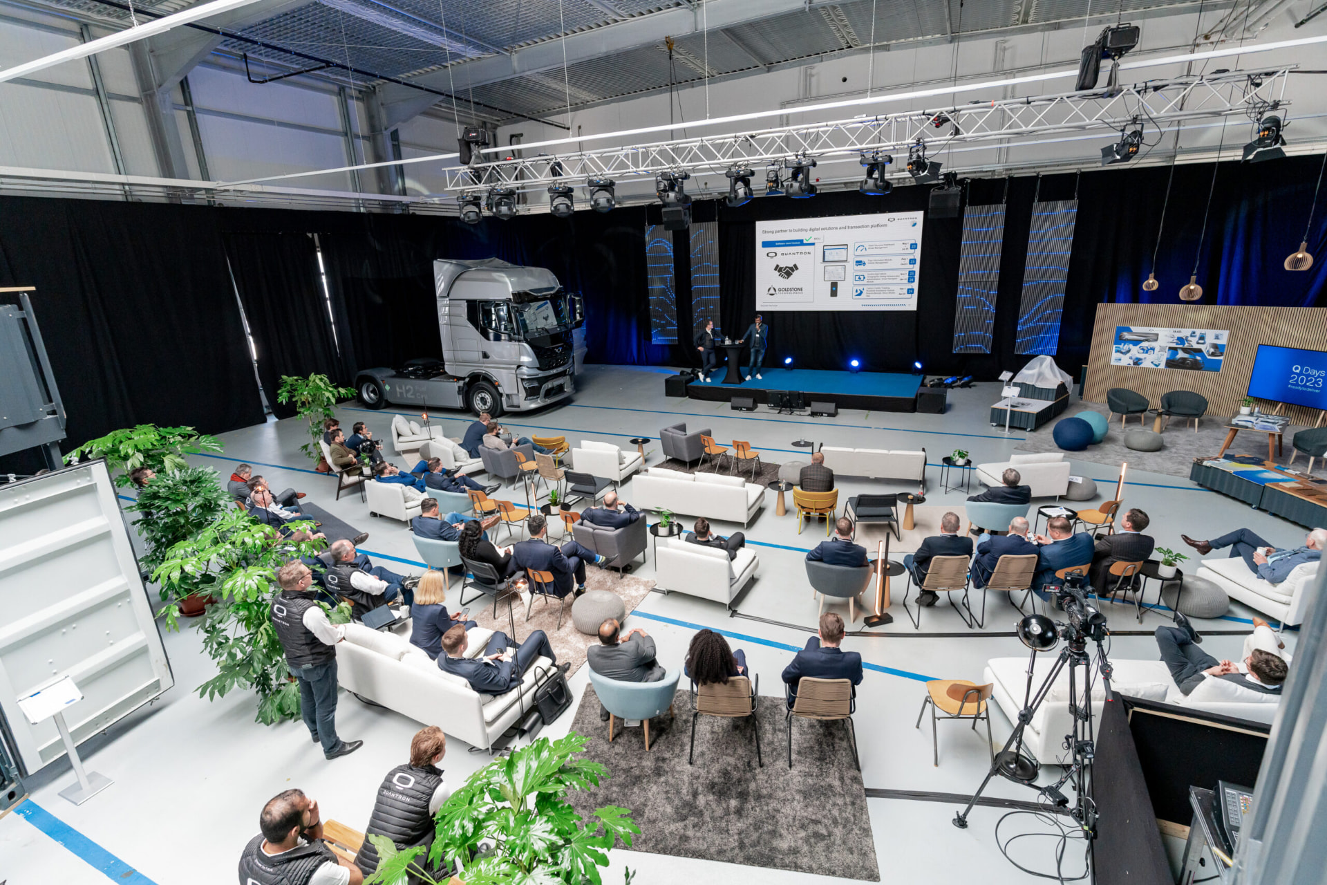 Konferenz in einer Halle mit Bühne, Lounge-Möbeln und Publikum